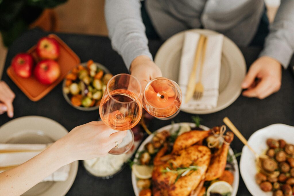 A festive holiday dinner scene with people toasting wine glasses over a delicious meal.