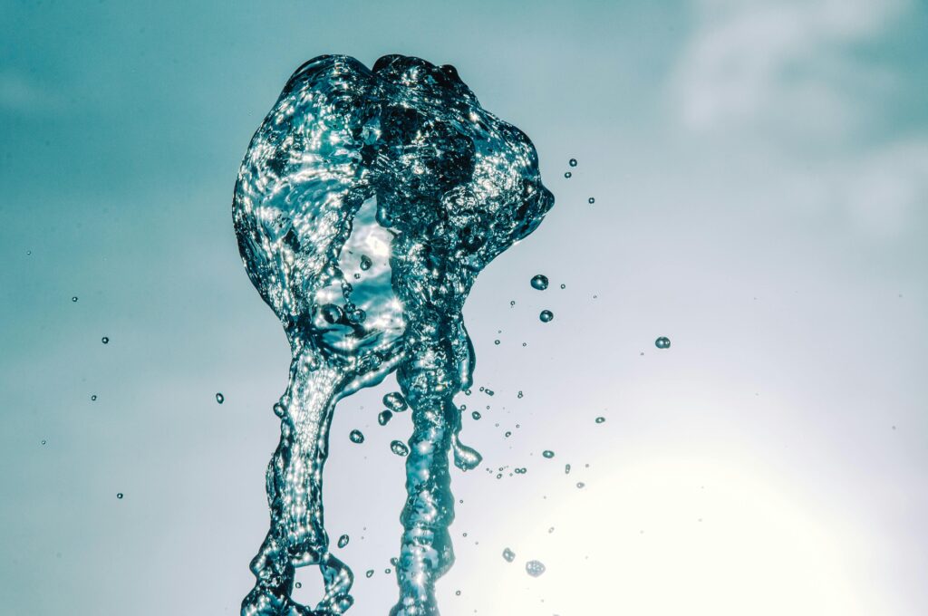 Close-up of water splash in mid-air against a bright sky, capturing motion and transparency.