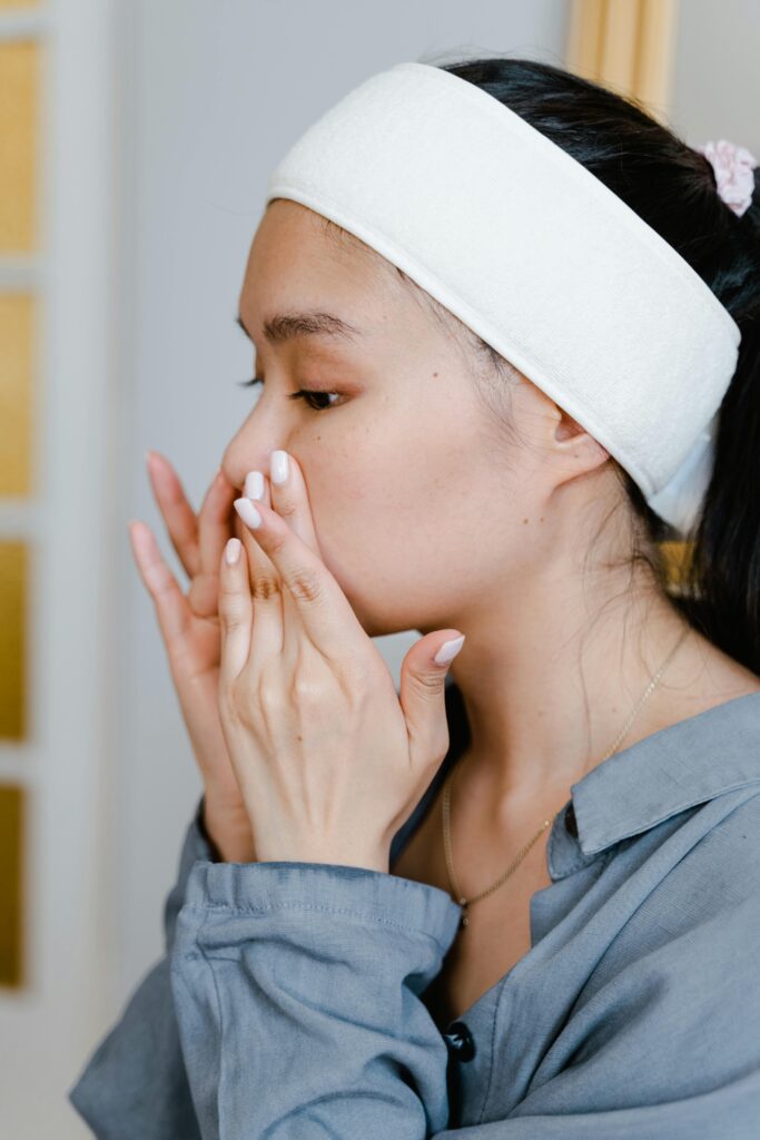 Close-up of an Asian woman applying facial skincare product indoors, focusing on beauty routine.
