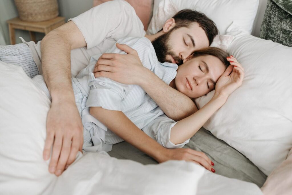 A loving couple embraces warmly in a cozy bedroom setting.