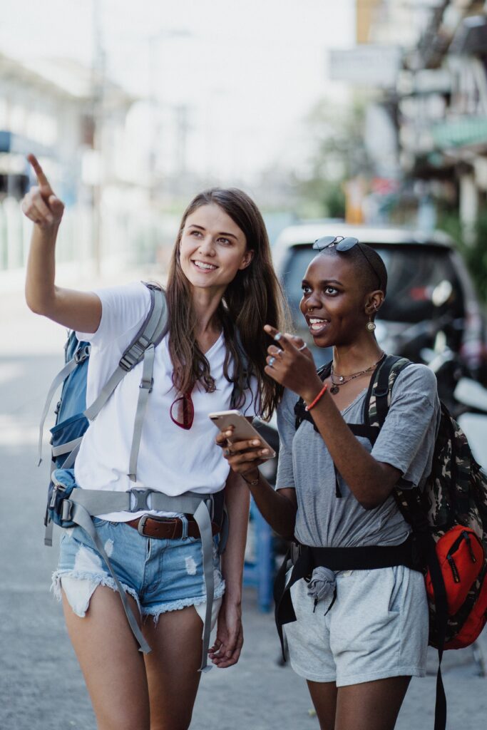 Two young women with backpacks exploring and enjoying city travel.