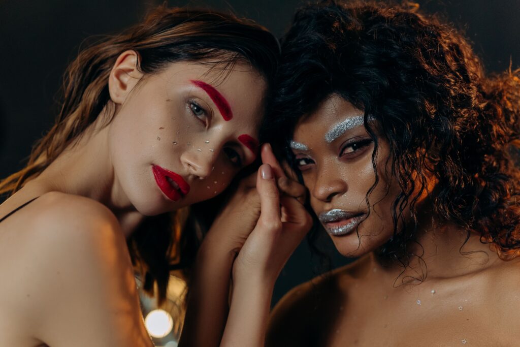 Vibrant artistic portrait featuring two women with bold makeup, embracing diversity and creativity.