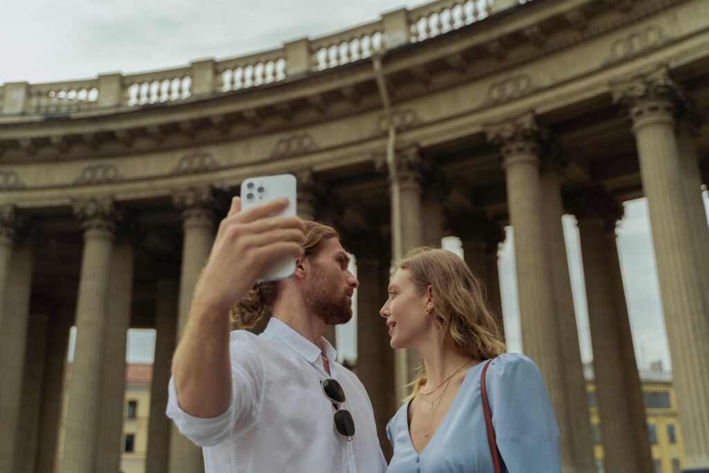 Couple capturing a selfie in front of a classical architectural landmark with pillars.